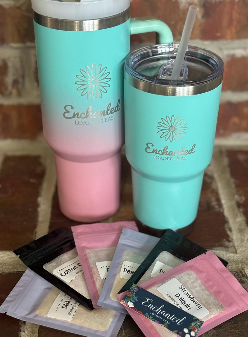 Puede incluir: Dos vasos de acero inoxidable turquesa y rosa con tapas y pajitas. Los vasos tienen el logotipo "Enchanted Loaded Teas" y un dise&ntilde;o de flores. Hay seis peque&ntilde;as bolsas de mezcla de t&eacute; con diferentes sabores, incluyendo "Strawberry Daiquiri" y "Cotton Candy".