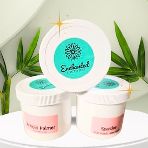 Puede incluir: Tres frascos blancos con tapas y etiquetas de color turquesa. El frasco de arriba tiene una etiqueta turquesa con una margarita blanca y el texto "Enchanted Loaded Teas". El frasco de la izquierda tiene una etiqueta rosa con el texto "Arnold Palmer Lemonade & Tea". El frasco de la derecha tiene una etiqueta rosa con el texto "Sparkles Fruit Punch Green Tea".