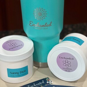 Puede incluir: Un vaso turquesa con tapa plateada y una pajita. El vaso tiene una pegatina blanca con el texto "Enchanted Loaded Teas" y un dise&ntilde;o de flor. Hay dos tarros blancos con etiquetas que dicen "Enchanted Loaded Teas" y "Sunny Daze Orange, Pineapple, Peach Tea". Hay una tarjeta de visita con el texto "Pide en Etsy @enchantedteabyalicia Sean & Alicia Hedrick EnchantedTeas@outlook.com"