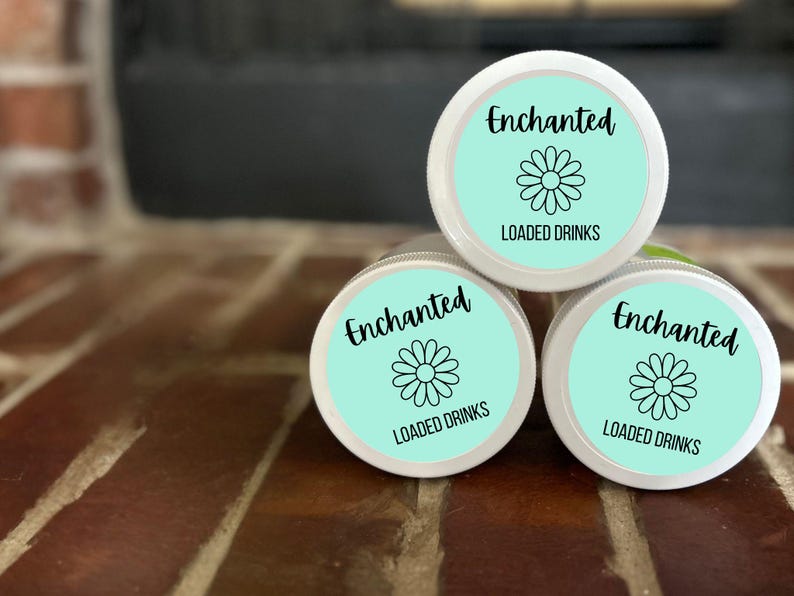 May include: Three white containers with turquoise lids and labels that say "Enchanted Loaded Drinks" with a black daisy graphic.