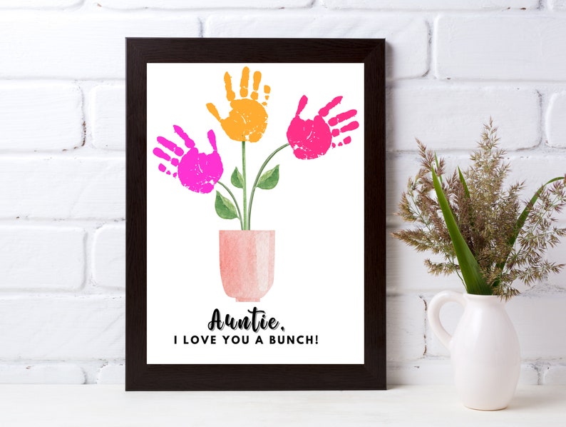 May include: A framed print with a handprint flower bouquet in pink and orange. The vase is a light pink watercolor style. The text reads "Auntie, I love you a bunch!"