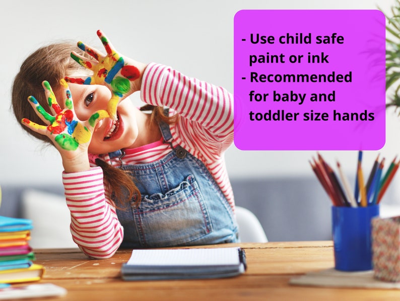 May include: A young girl with colorful paint on her hands smiles at the camera. The text on the pink note reads: "Use child safe paint or ink - Recommended for baby and toddler size hands".