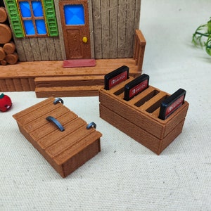 May include: A wooden storage box with a hinged lid and a metal handle. Next to it is a wooden stand with slots for holding Nintendo Switch game cartridges. The stand has the text "Nintendo Switch" printed on the front.