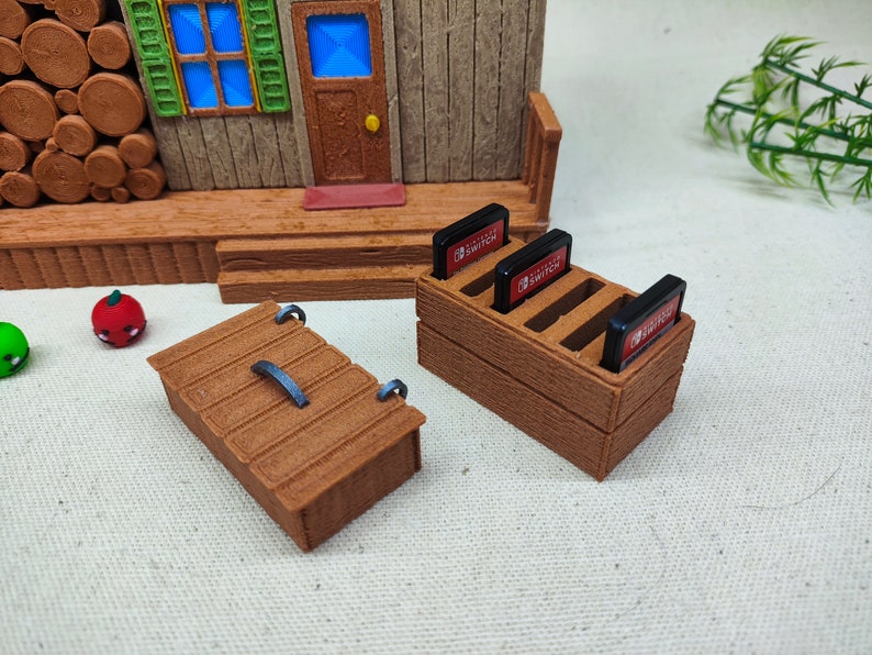 May include: A wooden storage box with a hinged lid and a metal handle. Next to it is a wooden stand with slots for holding Nintendo Switch game cartridges. The stand has the text "Nintendo Switch" printed on the front.