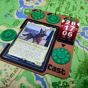 May include: A brown and green game board with a card that reads "Albondiga, siempre leal" and a red and white counter with the numbers 28, 17, 06, and 95. The board has a green circle with the numbers 1, 2, 3, 4, 5, 6, 7, 8, 9, 10, 11, and 12. The board also has the word "cast" printed on it.