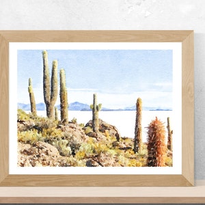 May include: Watercolor painting of a desert landscape with tall cacti and a distant view of a lake. The sky is a light blue and the water is a pale blue. The cacti are green and brown and the rocks are brown and gray.