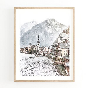 May include: A watercolour painting depicting a quaint village nestled in a snowy mountain valley. The village sits on the edge of a lake, with a church spire rising above the rooftops. The mountains in the background are covered in snow and the sky is a soft grey.