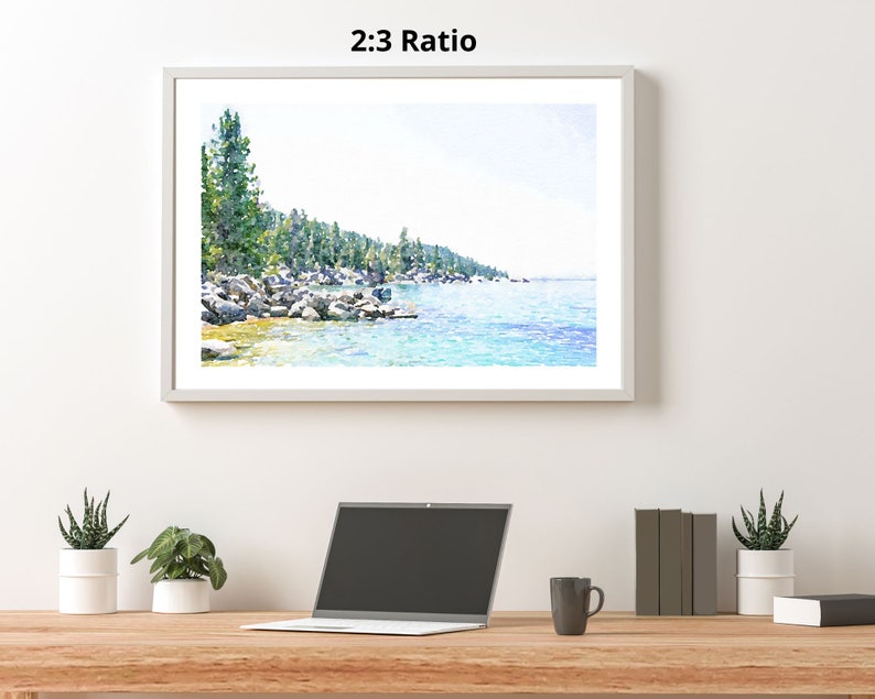 May include: A watercolor painting of a lake scene with a shoreline of trees and rocks. The water is a light blue and the sky is a light blue with white clouds. The painting is framed in a white frame.