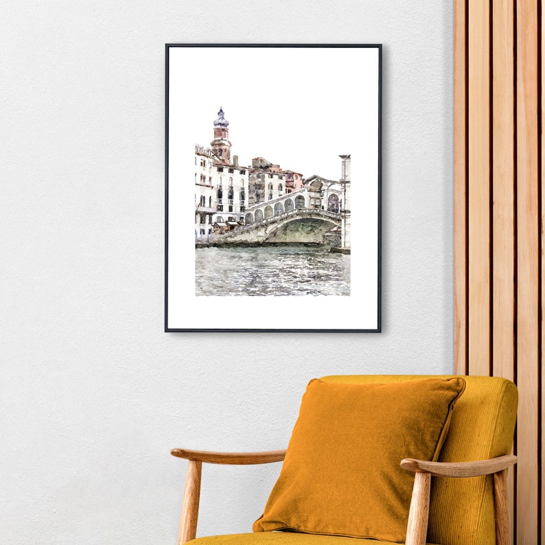 Puede incluir: Una impresi&oacute;n en acuarela enmarcada de un puente veneciano sobre un canal. La obra de arte presenta una representaci&oacute;n detallada del puente con edificios y una torre al fondo. La impresi&oacute;n est&aacute; en un marco negro y cuelga de una pared blanca.