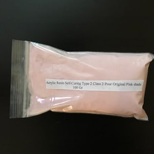 May include: A transparent plastic bag filled with pink powder. The bag features a white label with the text "Acrylic Resin Self-Curing Type 2 Class 2 Pour Original Pink shade 100 Gr".