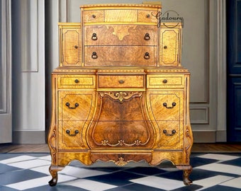 May include: A vintage wooden dresser with a curved top and intricate carvings. The dresser has multiple drawers and a small cabinet on top. The dresser is painted in a warm, honey-colored stain.
