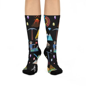 May include: A pair of black socks with a colourful design featuring a volcano, mountains, gems, pickaxes, and a warning sign that reads "Danger Rocks".