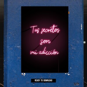 May include: A neon sign with the Spanish phrase "Tus secretos son mi adicción" in pink script against a black background. The sign is mounted on a blue wall, with the words "READY TO DOWNLOAD" at the bottom.