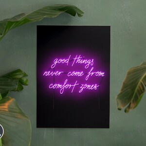 Op de afbeelding: Een zwarte poster met een roze neon-bord met de tekst "good things never come from comfort zones". De poster hangt aan een groene muur met groene planten aan beide kanten.