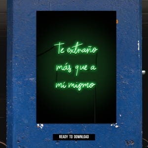May include: A neon sign with the Spanish phrase "Te extraño más que a mí mismo" in green script against a black background. The sign is mounted on a blue wall. The words translate to "I miss you more than myself."