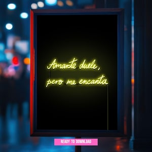 May include: A framed black sign with neon yellow text that reads "Amarte duele, pero me encanta." The sign has a red border and a pink "READY TO DOWNLOAD" button at the bottom. The background is a blurred city scene.