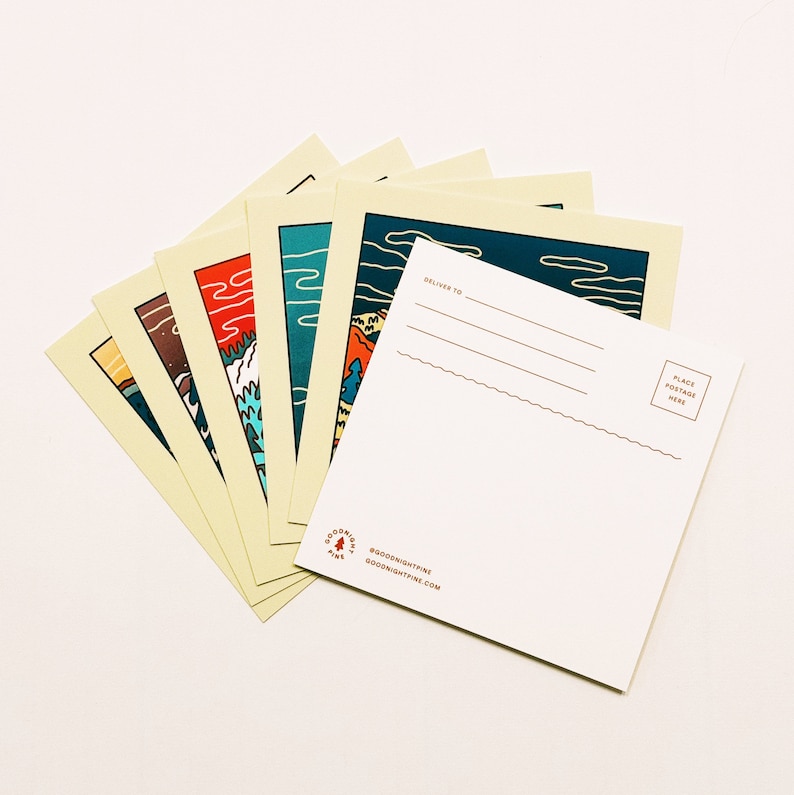 May include: Set of six illustrated postcards featuring different mountain scenes. The postcards are printed on cream-colored cardstock with a white back for writing. The back of the postcards includes the text "Goodnight Pine" and a website address.