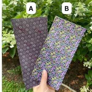 May include: Two sheets of decorative paper with different patterns. One sheet has a black background with a white circle pattern. The other sheet has a black background with a colorful geometric pattern.