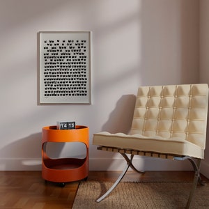 Peut inclure: Une chaise blanche avec un dossier capitonn&eacute; et des pieds chrom&eacute;s se trouve dans une pi&egrave;ce avec un mur blanc et une impression noir et blanc sur le mur. Une petite table d'appoint orange avec une horloge sur le dessus se trouve &agrave; c&ocirc;t&eacute; de la chaise.