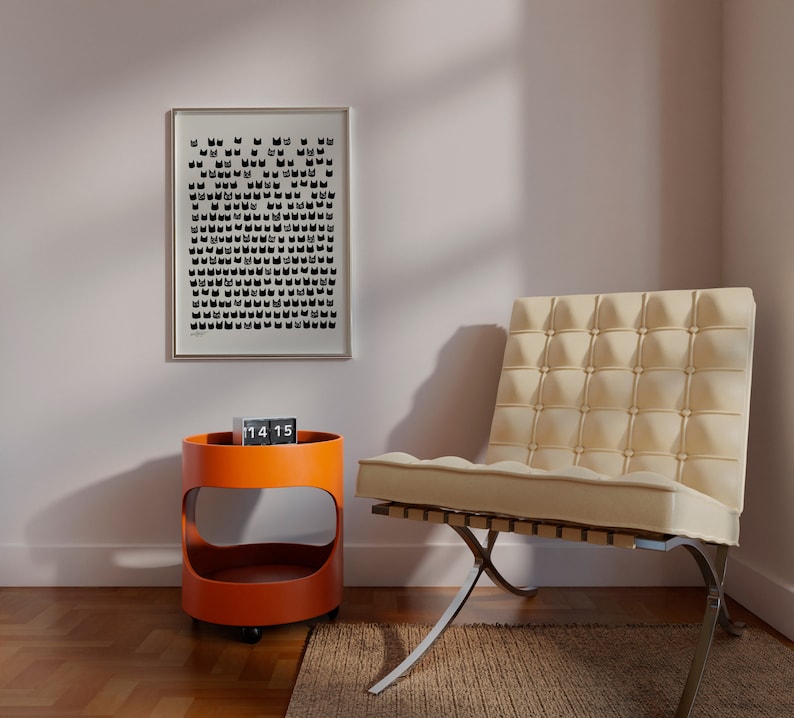Peut inclure: Une chaise blanche avec un dossier capitonn&eacute; et des pieds chrom&eacute;s se trouve dans une pi&egrave;ce avec un mur blanc et une impression noir et blanc sur le mur. Une petite table d'appoint orange avec une horloge sur le dessus se trouve &agrave; c&ocirc;t&eacute; de la chaise.