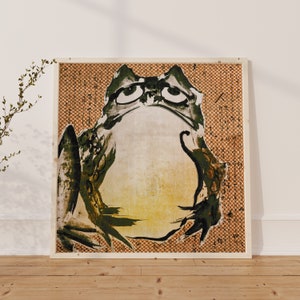 May include: A framed print of a green and yellow frog with large eyes, set against a brown and white checkered background.