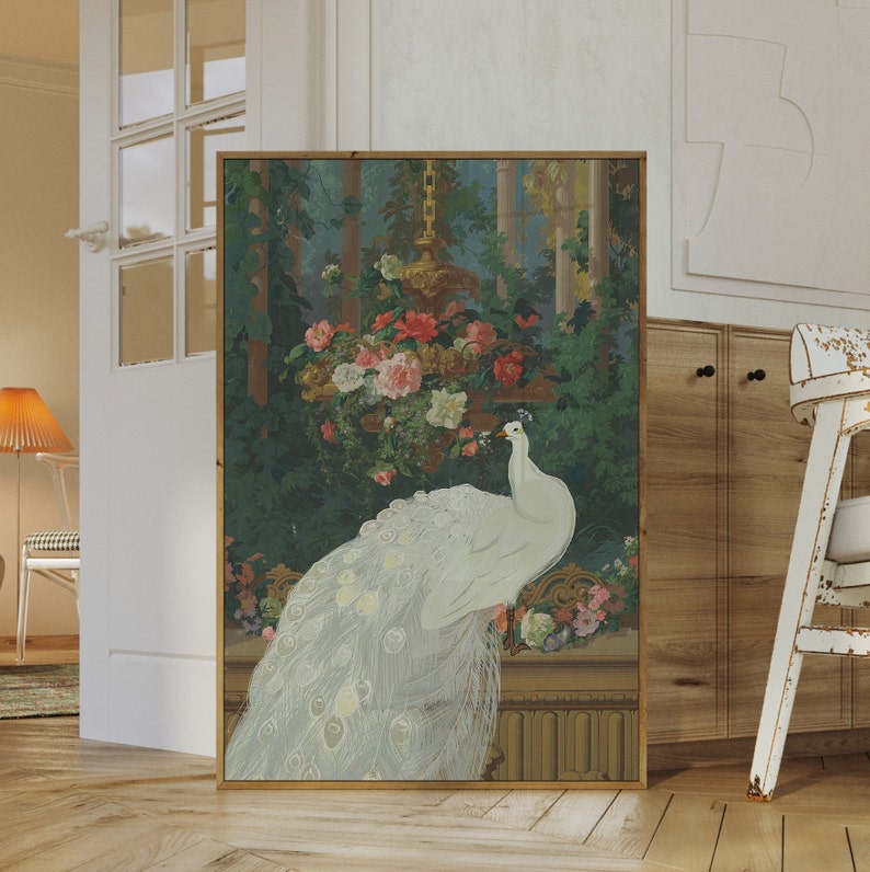 May include: A framed art print featuring a white peacock with a long, flowing tail. The artwork depicts the peacock perched on a decorative ledge, with a backdrop of lush greenery, flowers, and a hanging floral arrangement. The frame is a warm, natural wood tone.