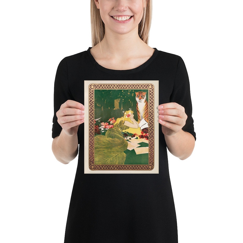 May include: A vintage illustration of a woman in a green dress with a tiger standing behind her. The woman is reading a book and there are flowers around her. The illustration is surrounded by a decorative border.