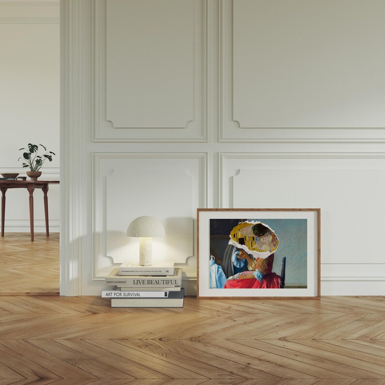 Puede incluir: Una pintura enmarcada de una mujer con un vestido rojo y un sombrero amarillo y azul. La pintura est&aacute; colgada en una pared blanca con moldura blanca. Hay libros apilados en una mesa debajo de la pintura, incluyendo "Live Beautiful" y "Art for Survival".
