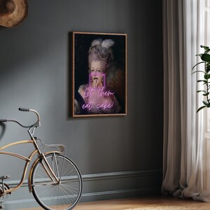 May include: A painting of a woman in a white dress and a crown, with the text "Let them eat cake!" in pink neon letters.