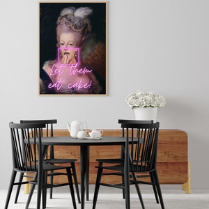 May include: A framed print of a painting of a woman in a white dress and a crown. The woman is holding her hand to her mouth and the text "Let them eat cake!" is written in pink neon letters.