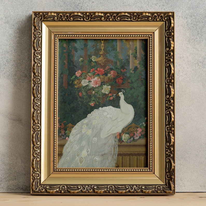 May include: A framed painting featuring a white peacock with its tail feathers displayed. The artwork is set against a backdrop of flowers and foliage, framed in a gold ornate frame. The painting has a vintage aesthetic.
