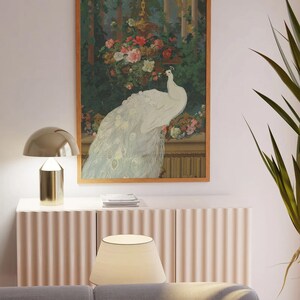 May include: A framed artwork featuring a white peacock with its tail feathers displayed. The artwork is set against a backdrop of lush greenery and flowers, with a gold-toned decorative element. The frame is a warm brown color.