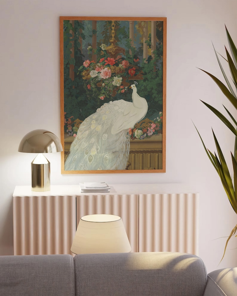 May include: A framed artwork featuring a white peacock with its tail feathers displayed. The artwork is set against a backdrop of lush greenery and flowers, with a gold-toned decorative element. The frame is a warm brown color.