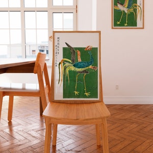 May include: A framed print of a colorful bird with a long tail, set against a green background. The print is in a wooden frame and is hanging on a wall. The text on the print is in Japanese.