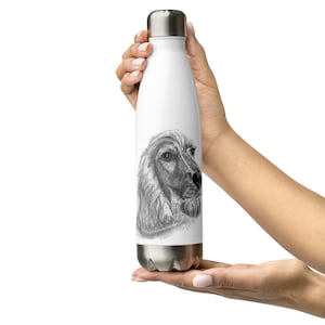 Puede incluir: Una botella de agua de acero inoxidable blanca con un boceto en blanco y negro de la cabeza de un perro en la parte delantera.