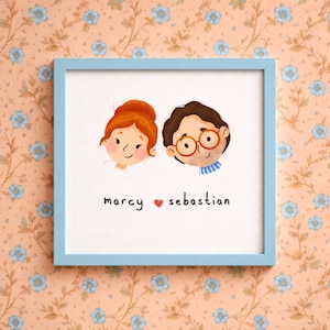 Könnte beinhalten: Gerahmte Illustration mit zwei Cartoon-Gesichtern, eines mit rotem Haar und das andere mit braunem Haar und Brille. Die Namen "marcy" und "sebastian" stehen darunter mit einem Herzsymbol dazwischen. Der Rahmen ist hellblau.