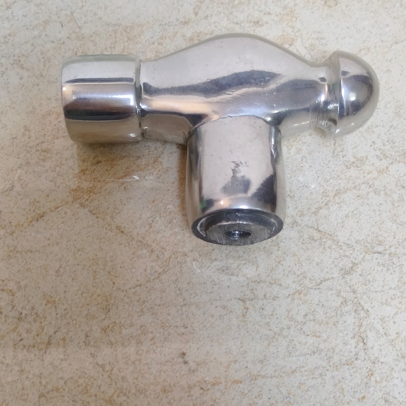 May include: A silver hammer with a rounded head and a square handle. The hammer is made of metal and has a shiny finish.