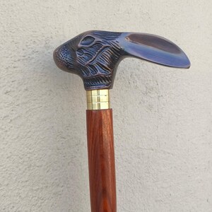 Può includere: Un bastone da passeggio con un'impugnatura a forma di testa di coniglio in bronzo dettagliata. L'impugnatura è attaccata a un'asta di legno con un collare in ottone. La testa di coniglio ha dettagli intricati e il legno ha una finitura scura.