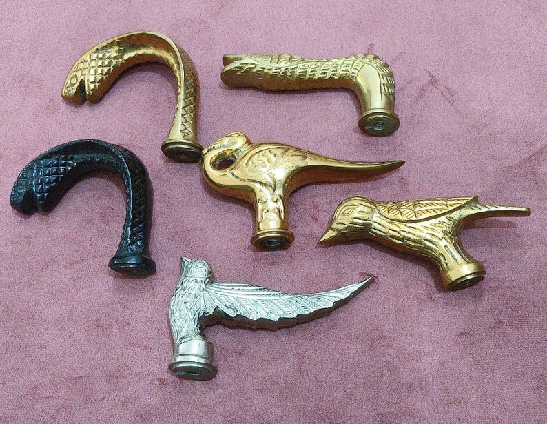May include: Six different cane handles, each with a unique design. The handles are made of metal and feature a variety of animal and abstract shapes. The handles are all gold, silver, and black in color.