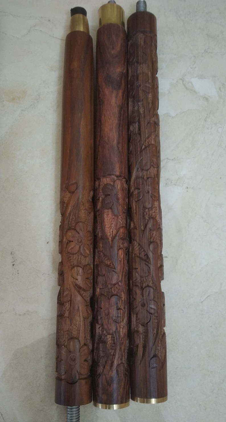 Op de afbeelding: Drie cilindrische houten wandelstoksegmenten met gedetailleerde bloemmotieven. Elk segment vertoont een rijke bruine houtnerf en is voorzien van metalen connectoren aan de uiteinden, inclusief metalen schroefverbindingen voor de montage.