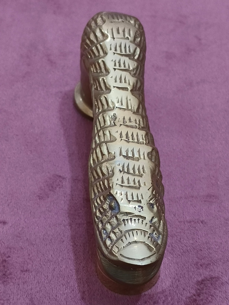 May include: A gold-colored metal door handle shaped like a snake with a textured surface.