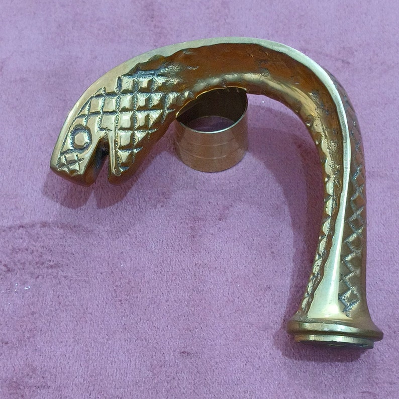 May include: A gold-colored metal snake-shaped walking stick handle. The handle is detailed with scales and a snake head.