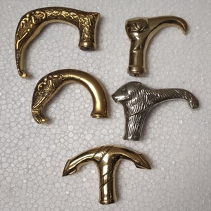 Può includere: Cinque manici di bastone diversi, ognuno con un designo animale unico. I manici sono in metallo e hanno una finitura lucida. I design includono un elefante, un uccello, un leone e altri due design di animali.