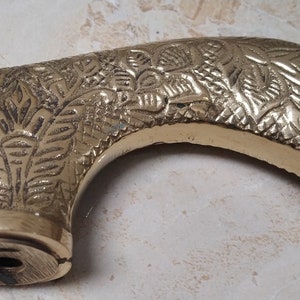 May include: A gold-colored metal cane handle with an intricate floral design.