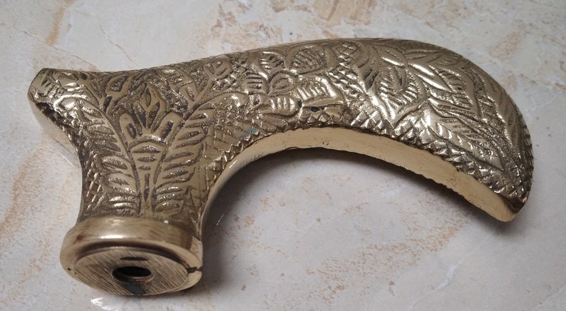 May include: A gold-colored metal cane handle with an intricate floral design.