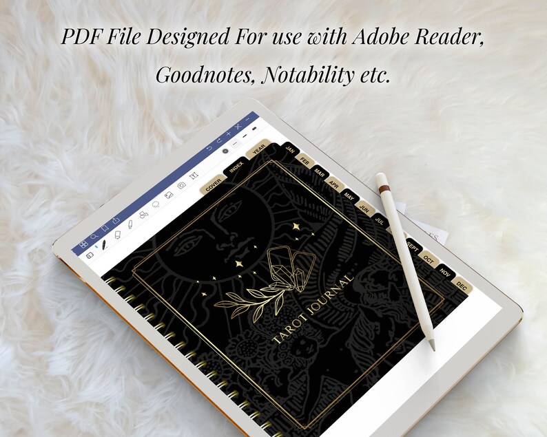 May include: A black and gold tarot journal with a sun and stars design on the cover. The journal has tabs for each month of the year. The journal is displayed on a tablet screen.