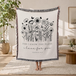 May include: Cream-coloured throw blanket featuring a black floral design and butterflies. The blanket has a fringed edge and the text "FOR I KNOW THE PLANS I HAVE FOR YOU" with the reference Jeremiah 29:11.
