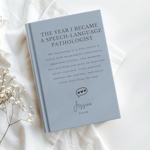 May include: A light blue hardcover book with the text THE YEAR I BECAME A SPEECH-LANGUAGE PATHOLOGIST, followed by a paragraph about a new career, a speech bubble icon with three hearts, the name Jessica, and the year 2026 printed in dark gray.
