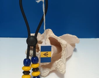 May include: A black elastic cord with blue and yellow beads and a black plastic toggle. A small tag with the flag of Barbados is attached to the cord.