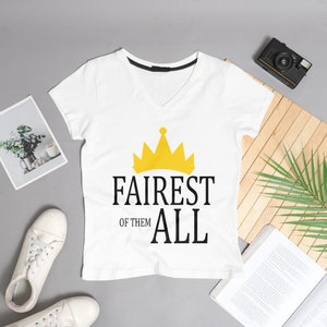 May include: White V-neck t-shirt with a gold crown graphic and the text "Fairest of them all".